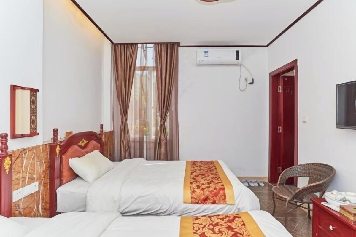Een hotelkamer met een bed, een stoel, een televisie en een airconditioning.