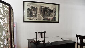 A room with a framed painting on the wall, a desk with a chair, and a decorative screen. - Heyang Bichenju (Hengyang)