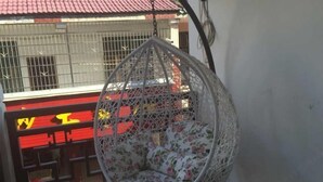 A hanging chair with a floral cushion, a red and yellow railing, and a metal gate in the background. - Heyang Bichenju (Hengyang)