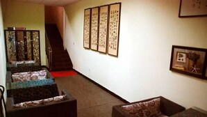 A room with a staircase, a sofa, a small table, and a wall with framed calligraphy. - Heyang Bichenju (Hengyang)