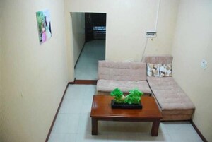 Un salón con un sofá, una mesa de centro con una planta y un cuadro en la pared.