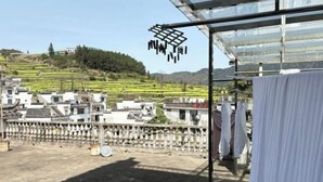 Terraza en la azotea con vistas a campos escalonados y un edificio lejano.