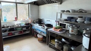 Una cocina con electrodomésticos de acero inoxidable, estantes con vajilla y una ventana con vistas.