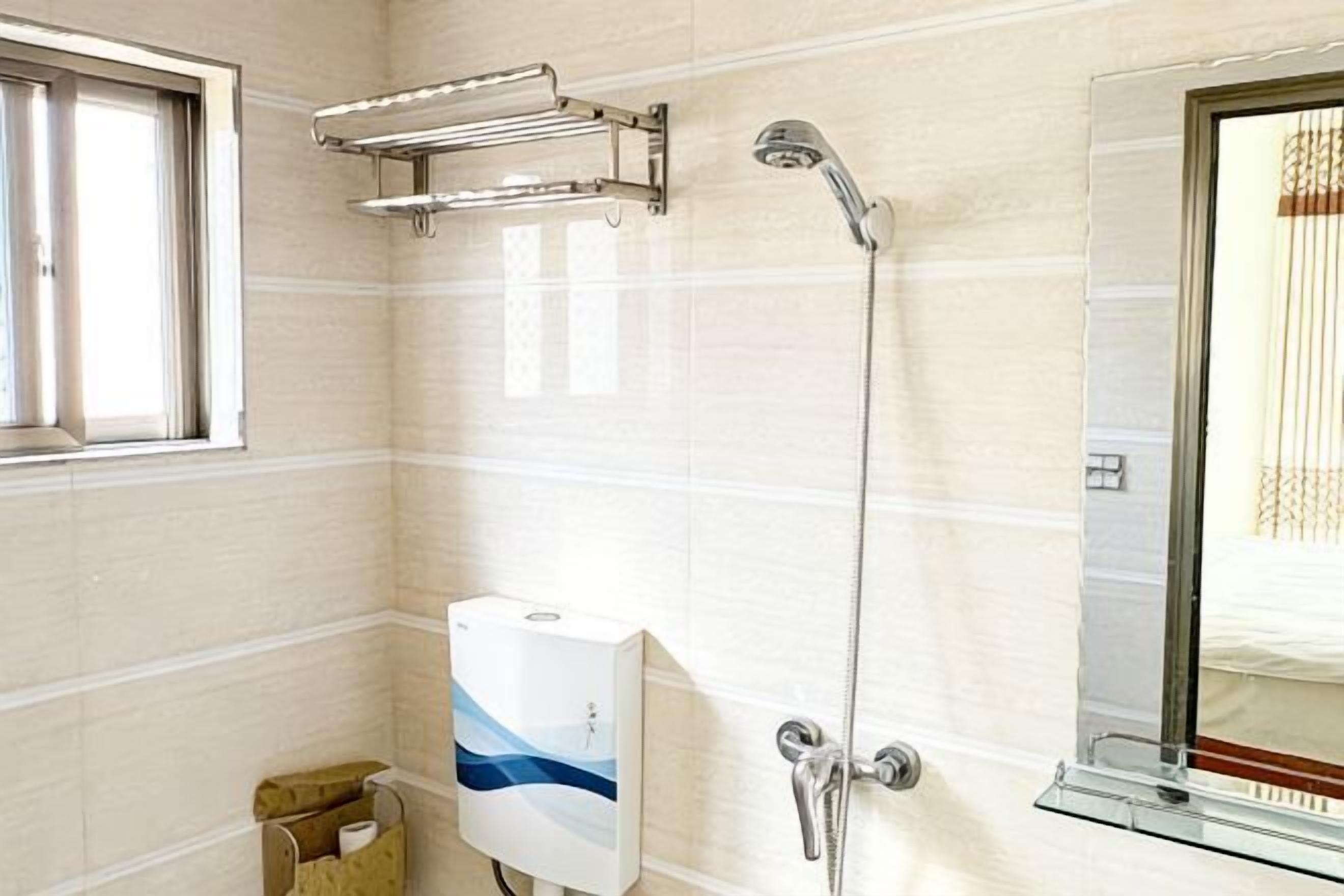 A bathroom with a shower, a towel rack, a hand dryer, and a window.