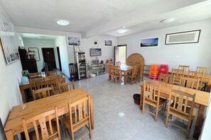 Un comedor con varias mesas y sillas de madera, un refrigerador y un microondas.