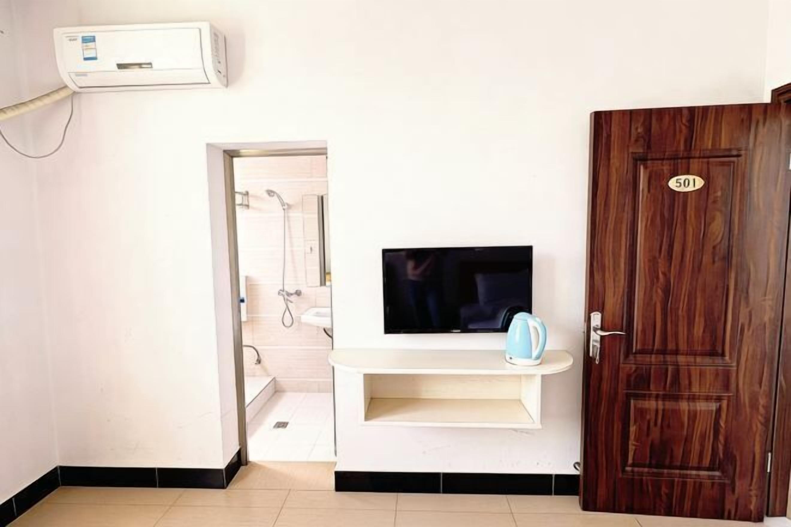 A room with a TV, a wooden door with a number, and a white wall.