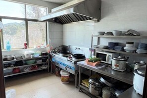 Una cocina con estufa, ollas y una ventana.
