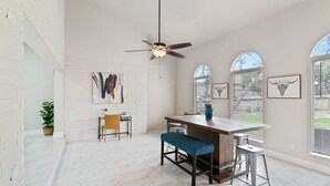 A spacious kitchen with a central island, white brick walls, and large windows.