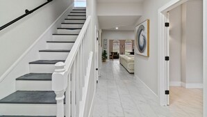A modern interior with a staircase, a living area with a sofa, and a painting on the wall.