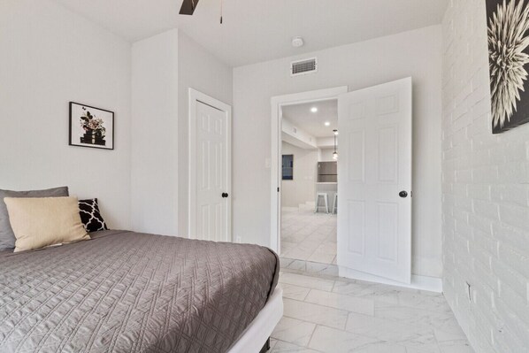 A bedroom with a bed, a door leading to a bathroom, and a hallway.