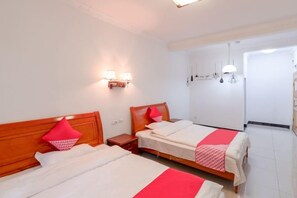 A hotel room with two beds, a nightstand, wall-mounted lamps, and a door leading to another room. - Tourist Hotel (Congjiang)