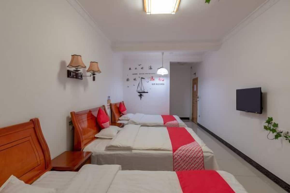 A hotel room with three beds, a television, and a wall with decorative elements.