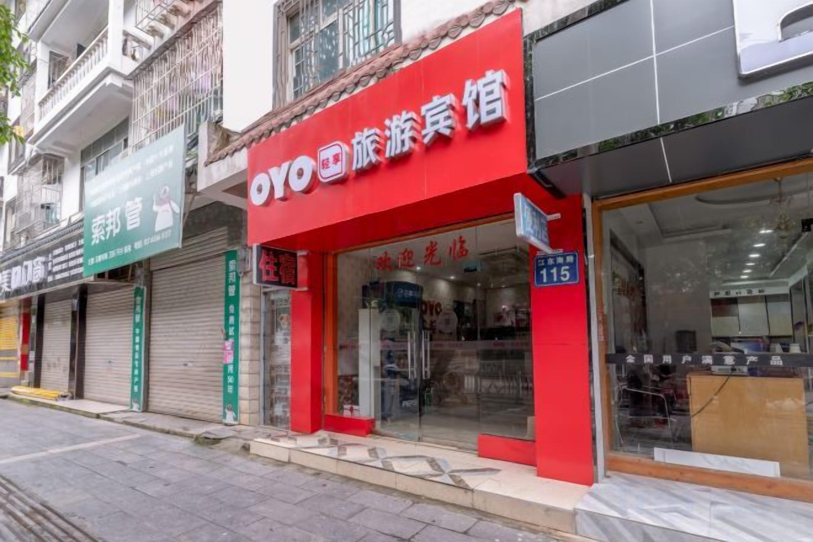 Un hotel con fachada roja, entrada visible y un cartel que indica la habitación 115.