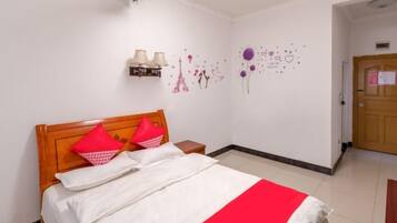A hotel room with a bed, a nightstand, a wall-mounted lamp, and a door.