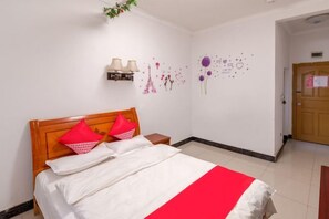 A hotel room with a bed, a nightstand, a wall-mounted lamp, and a door. - Tourist Hotel (Congjiang)