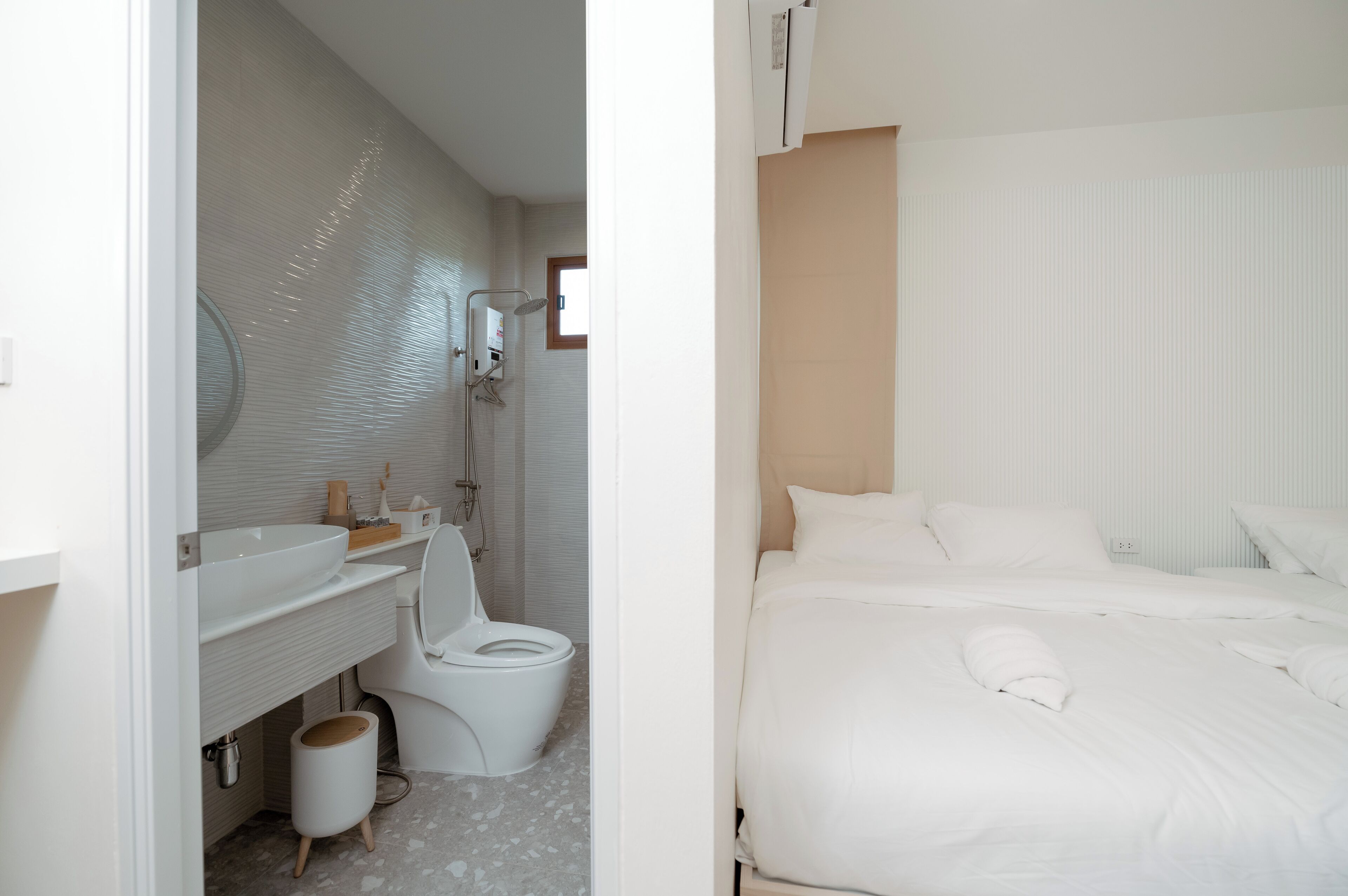 A modern bathroom with a white sink, toilet, and shower. The room has a clean, minimalist design with a tiled floor and a large mirror above the sink.