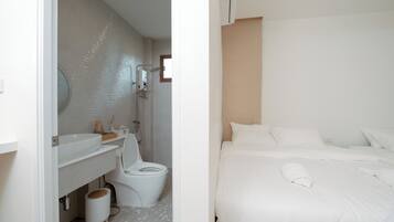 A modern bathroom with a white sink, toilet, and shower. The room has a clean, minimalist design with a tiled floor and a large mirror above the sink.