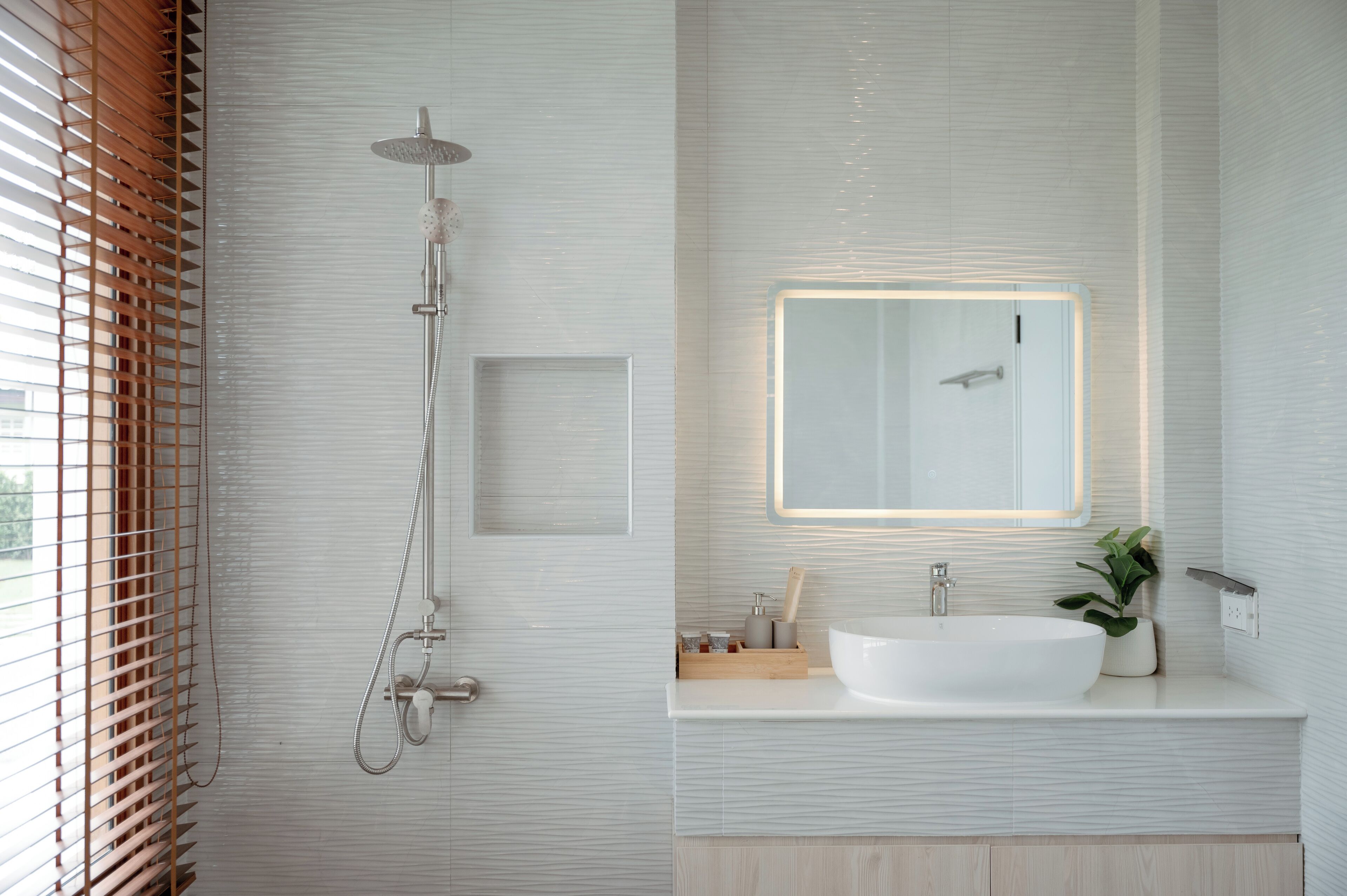 Une salle de bain moderne avec une douche, un grand miroir et un lavabo.