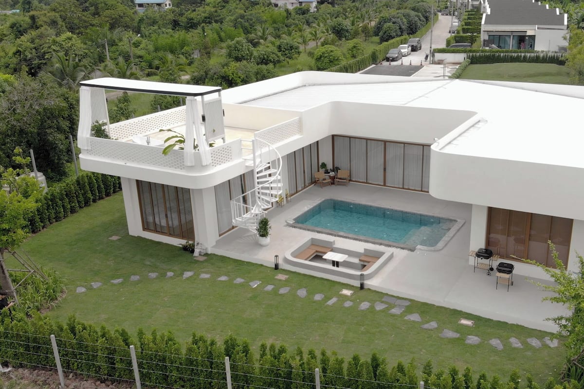 Una casa moderna con piscina, balcón y un jardín bien cuidado.