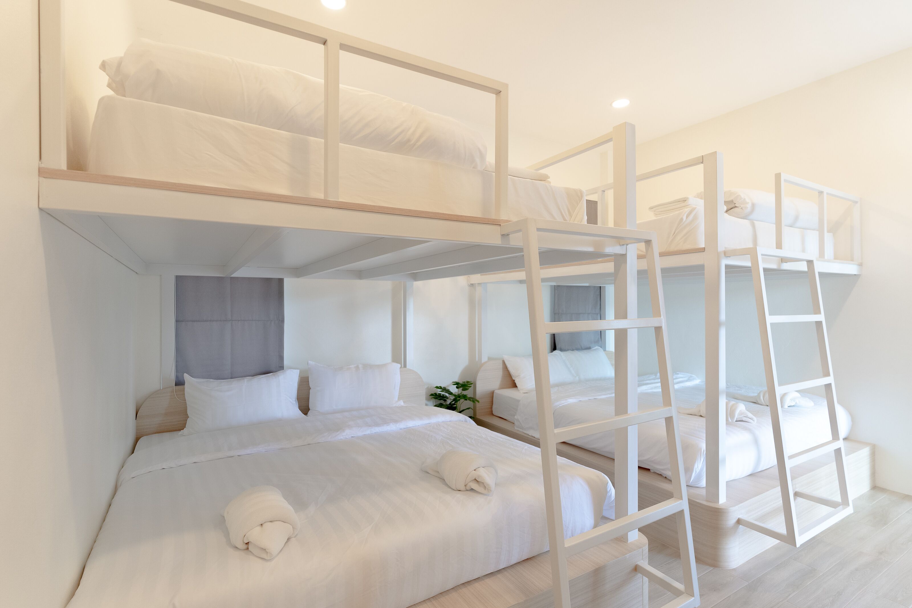 A bunk bed room with white bedding and a ladder.