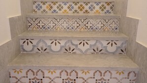 Un escalier à plusieurs volées, chaque marche étant ornée de carreaux aux motifs différents.