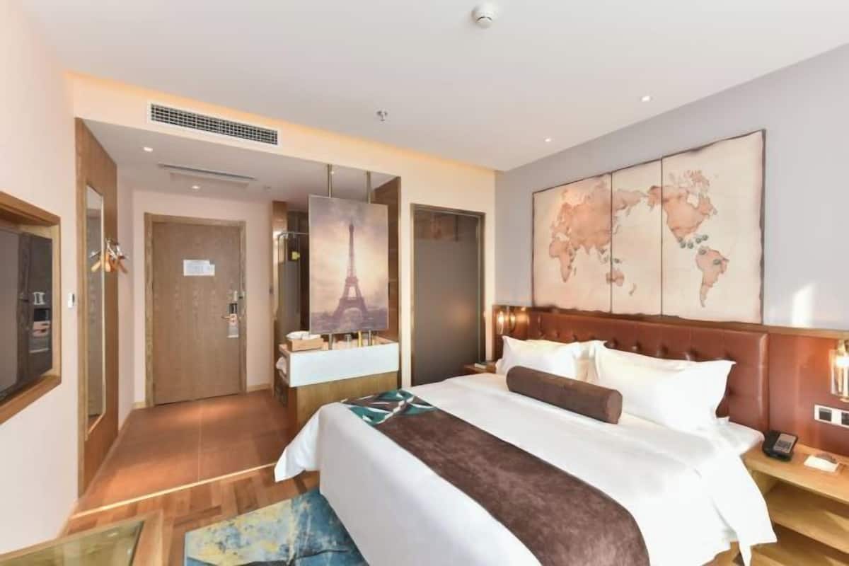 Une chambre d’hôtel avec un lit, une carte accrochée au mur, une vue sur la Tour Eiffel et un plancher en bois.