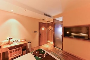 A hotel room with a wooden desk, a chair, a small table with a lamp, a trash bin, and a patterned rug. - James Joyce Coffetel (Beijing Happy Valley Fatou Metro Station) (Beijing)