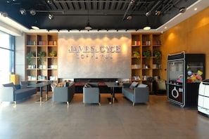 A modern coffee shop interior with a large wall-mounted sign, seating area, and bookshelves. - James Joyce Coffetel (Beijing Happy Valley Fatou Metro Station) (Beijing)