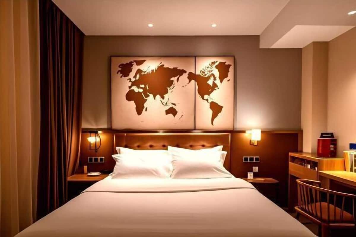 Une chambre d’hôtel avec un grand lit, deux tables de chevet, un bureau et une carte du monde accrochée au mur.