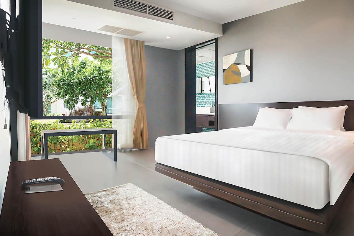 Un dormitorio moderno con una cama grande, un escritorio y vistas a zonas verdes.