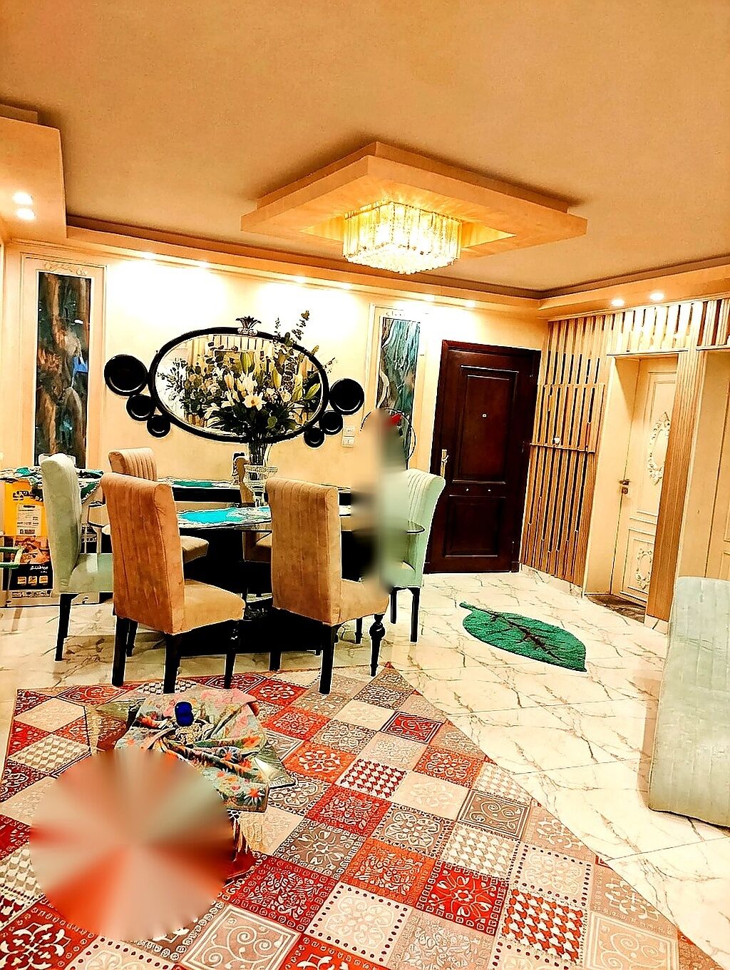 A dining area with a chandelier, a round table, and patterned rugs.