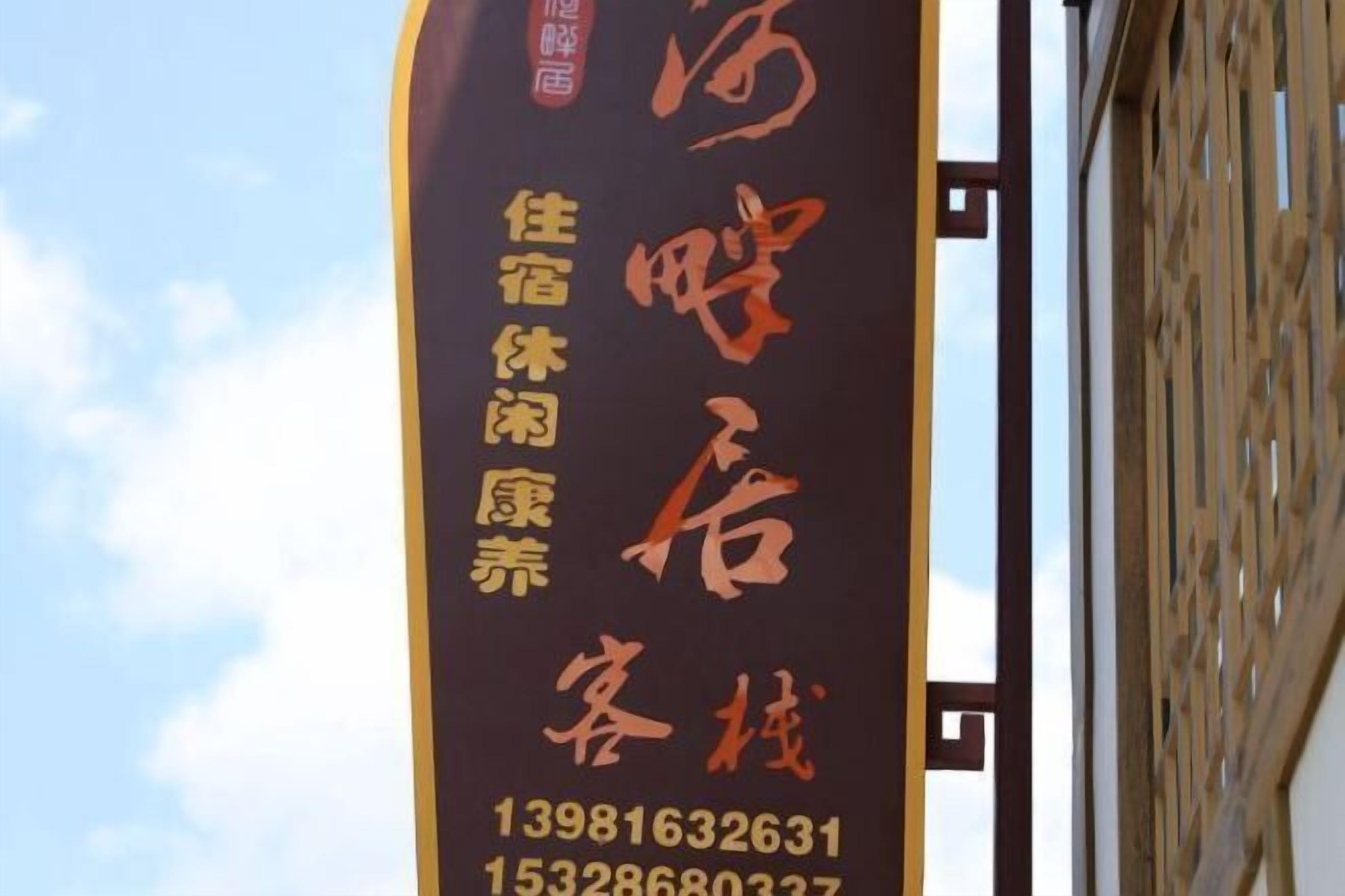 A vertical sign with Chinese characters and phone numbers for a hotel.