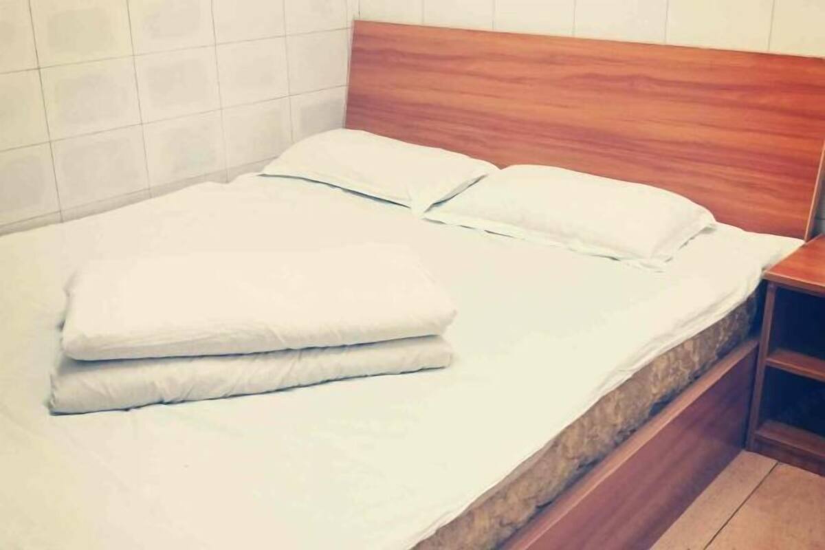 A bed with a wooden headboard, white bedding, and a wooden nightstand beside it.