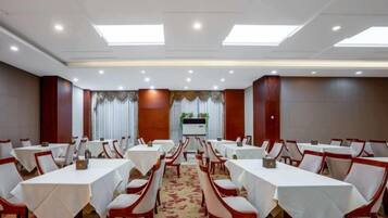 A conference room with multiple tables and chairs, a carpeted floor, and a neutral color scheme.