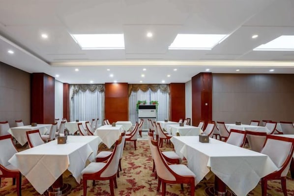 A conference room with multiple tables and chairs, a carpeted floor, and a neutral color scheme. - Xinghua Grand Hotel (Xinghua)