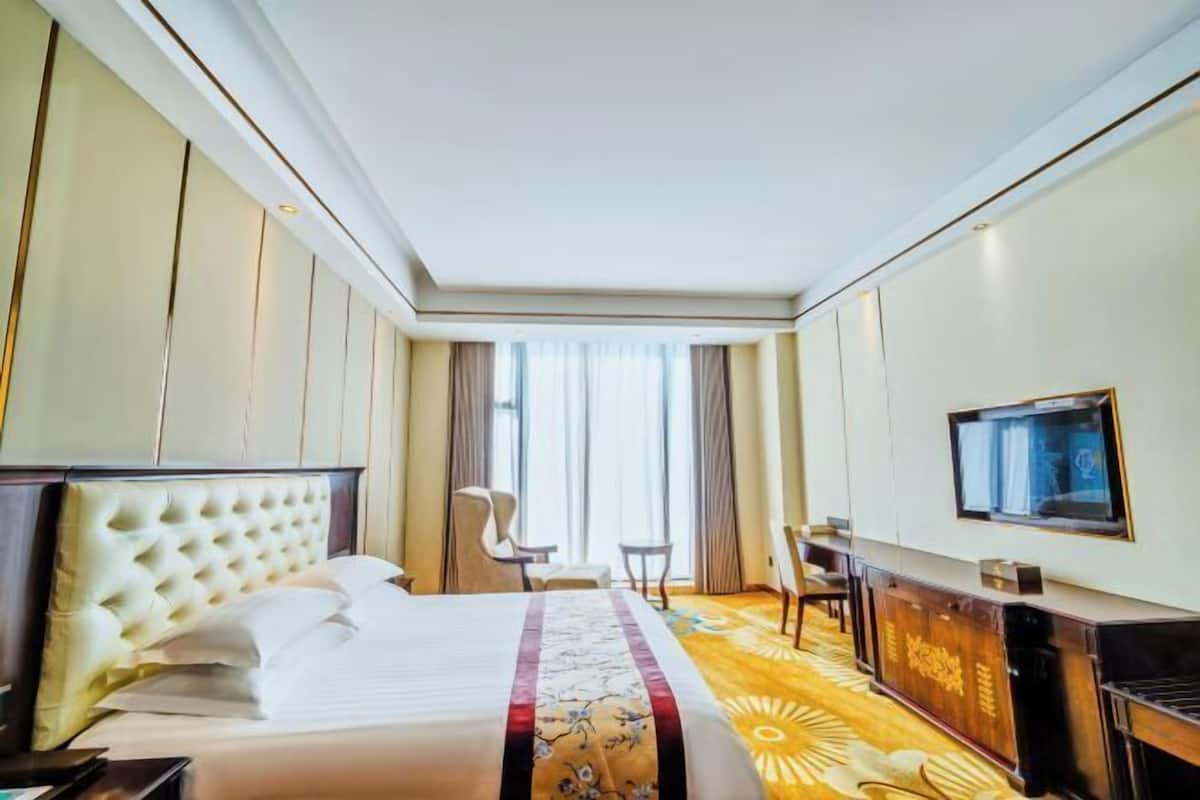 Une chambre d’hôtel avec un grand lit, un bureau, une chaise et un téléviseur.