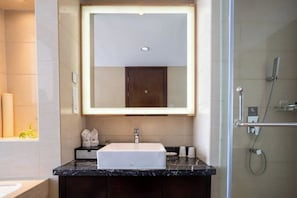 Un baño moderno con un espejo grande, un lavamanos blanco y una zona de ducha.