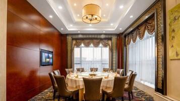 A conference room with a round table, chairs, and a large window with curtains.