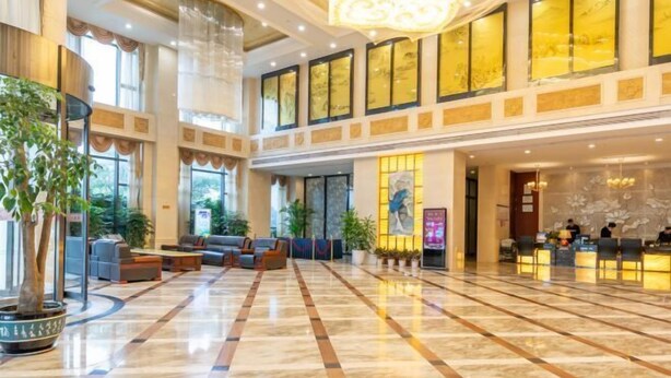 A spacious lobby with a checkered floor, seating areas, and a reception desk. - Xinghua Grand Hotel (Xinghua)