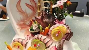 A table with a decorative centerpiece featuring a ceramic animal, flowers, and food items.