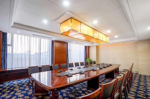 Una sala de conferencias con una mesa larga, sillas y una lámpara en el techo.