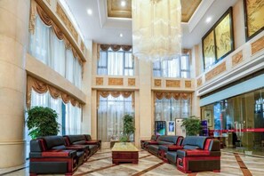 A spacious lobby with high ceilings, large windows, and a central seating area with sofas and a coffee table. - Xinghua Grand Hotel (Xinghua)