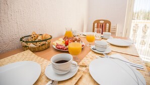 Ein Frühstückstisch ist gedeckt mit Tellern, Tassen und einem Brotkorb.
