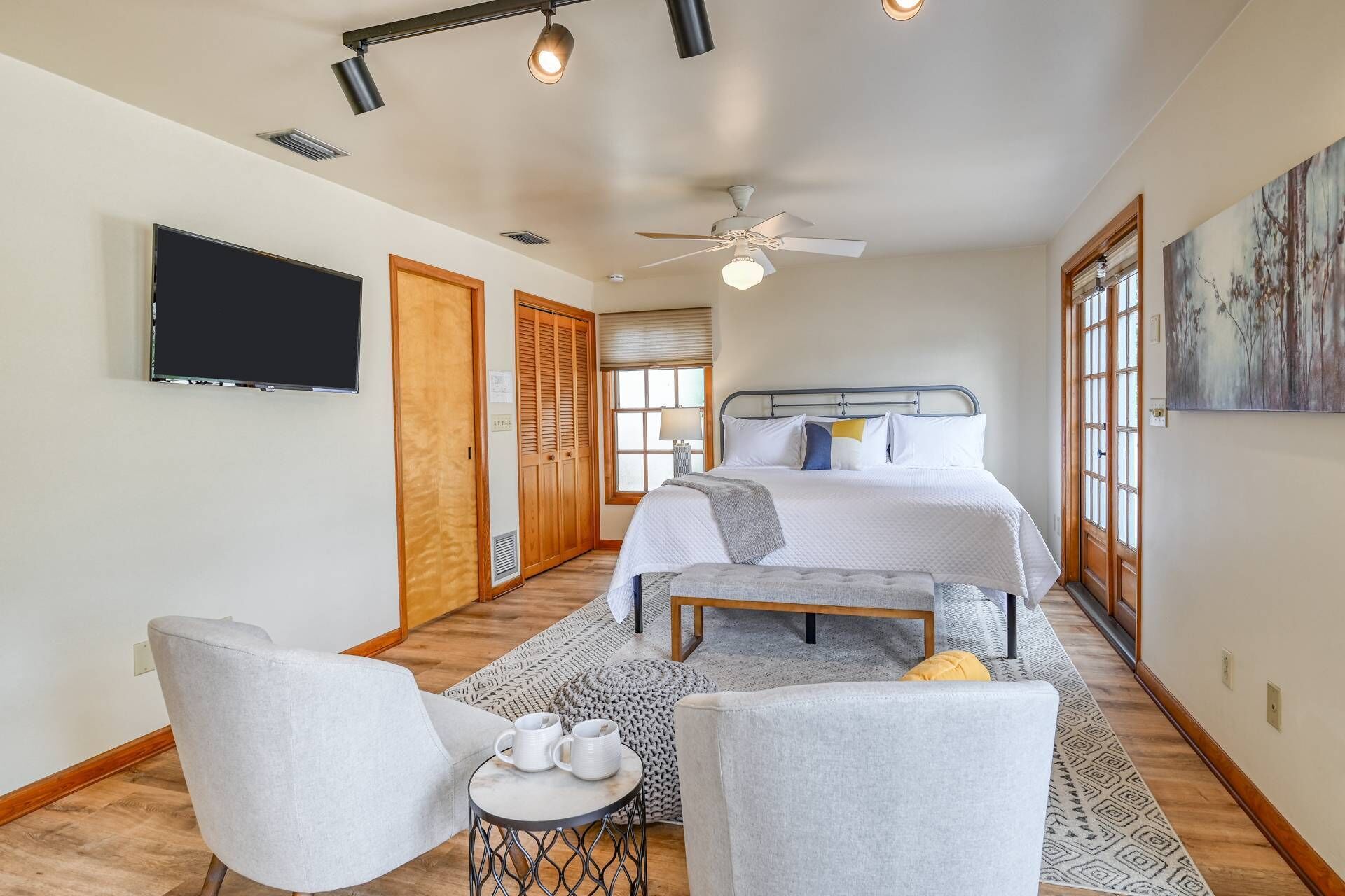 A bedroom with a bed, bedside tables, a TV, a ceiling fan, and a window.