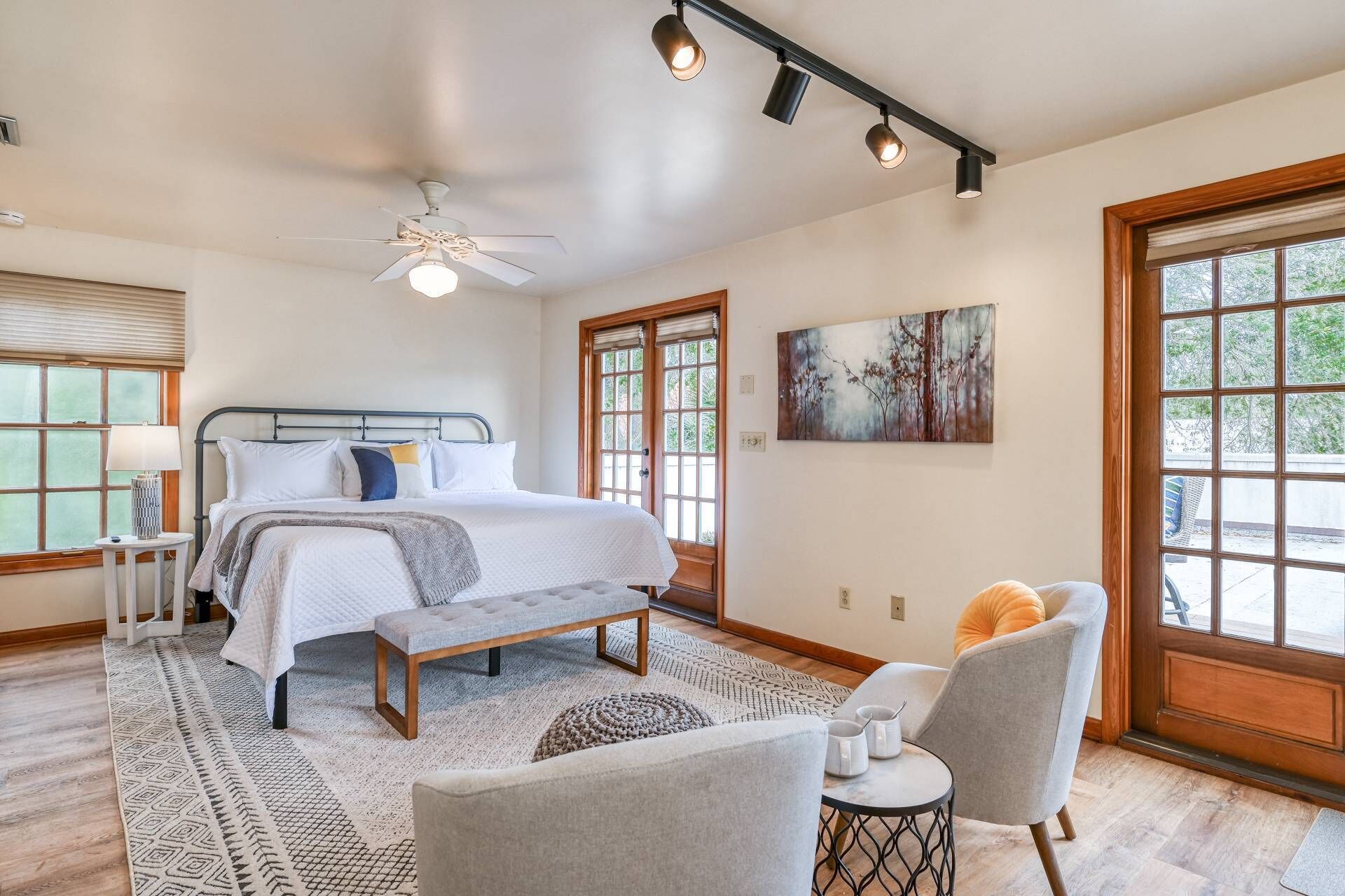 Une chambre à coucher comprenant un lit, une table de chevet, une lampe, un banc, une chaise et une œuvre d’art.