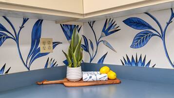 A kitchen corner with a blue countertop, a potted plant, a cutting board, and lemons.