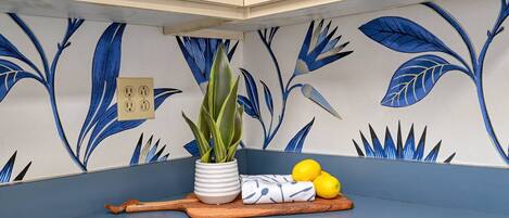 A kitchen corner with a blue countertop, a potted plant, a cutting board, and lemons.