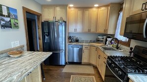 A kitchen with wooden cabinets, a stainless steel refrigerator, a gas stove, and a microwave.