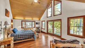 Un dormitorio amplio con una cama grande, muebles de madera y múltiples ventanas que ofrecen vistas al exterior.