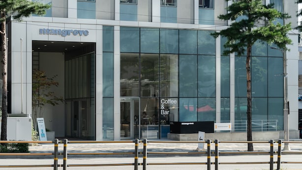 A modern building with a 'Mangrove Coffee & Bar' sign, large glass windows, and a visible entrance. - Mangrove Dongdaemun - Hostel (Seoul)